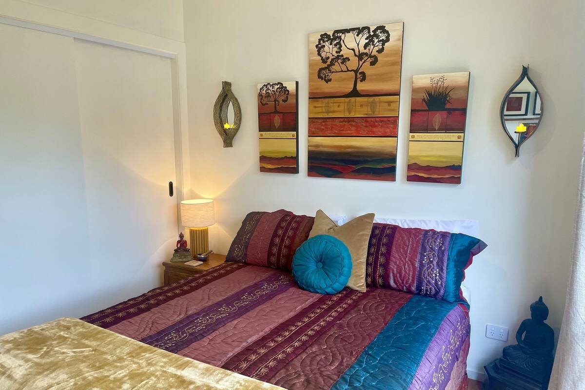 Un dormitorio con cama, mesita de noche, lámpara y decoración en la pared.