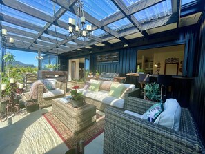 Un área de estar al aire libre con techo, muebles de mimbre y una parrilla.