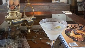 A cozy living room with a fireplace, a glass table with a martini glass, and a decorative lamp. - Ballygelvar (Cambridge)