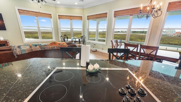 A kitchen with a large island, a dining area, and large windows with a view. - Waterfront Oasis w/ Dock, Sleeps 12 (Bay St. Louis)