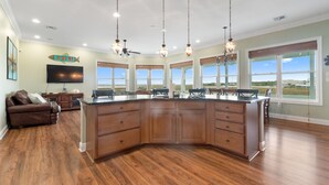 A spacious kitchen with a large island, wooden cabinets, and pendant lighting. - Waterfront Oasis w/ Dock, Sleeps 12 (Bay St. Louis)