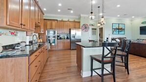 A spacious kitchen with wooden cabinets, a central island, and a dining area with chairs. - Waterfront Oasis w/ Dock, Sleeps 12 (Bay St. Louis)