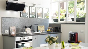 Una cocina moderna con horno empotrado, cafetera y ventana con plantas en macetas.