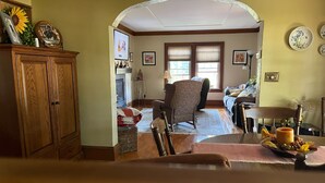 Un salon chaleureux avec une cheminée, un fauteuil à motifs et une table à manger agrémentée d’un centre de table.