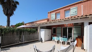Un'area patio con posti a sedere all'aperto, un frigorifero bianco e un tavolo da pranzo con sedie.