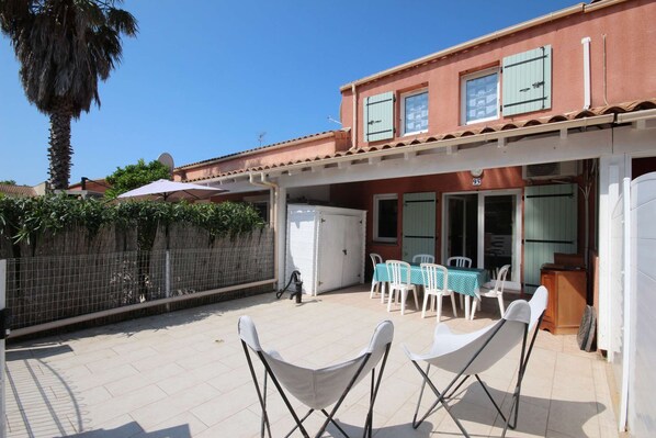A patio area with outdoor seating, a white refrigerator, and a dining table with chairs.