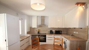 Una cucina moderna con mobili bianchi, un tavolo da pranzo in legno e una lavatrice integrata.