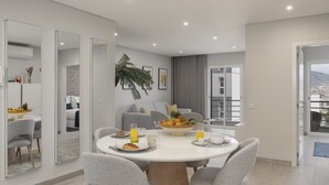 Een moderne eetruimte met een ronde tafel, grijze stoelen en een fruitschaal.