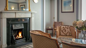 A cozy living room with a fireplace, patterned furniture, and a glass coffee table. - Dryfesdale Hotel, Bw Signature Collection (Lockerbie)