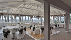 A banquet hall with white tables, chairs with black sashes, and a large window overlooking a landscape. - Dryfesdale Hotel, Bw Signature Collection (Lockerbie)