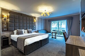 A modern bedroom with a large bed, a sofa, a desk, and a view of the outdoors. - Dryfesdale Hotel, Bw Signature Collection (Lockerbie)