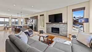 Una sala de estar amplia con chimenea de piedra, televisor grande y comedor con muebles modernos.
