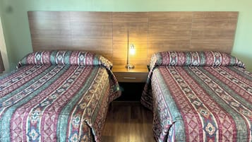 A double bed with patterned bedding, a wooden headboard, and a bedside lamp.