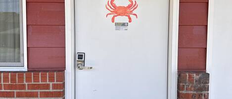A white door with the number 102, a red crab decal, and a small sign.