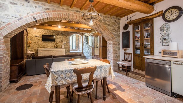 Una cucina rustica con parete in pietra, travi in legno e zona pranzo con tavolo e sedie.
