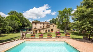 Un edificio in pietra con una piscina di fronte.
