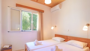 Une chambre d’hôtel avec deux lits, une petite table et une fenêtre avec des rideaux.