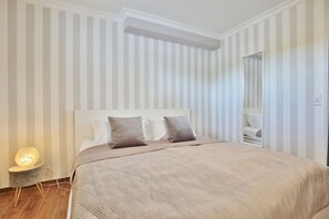 Une chambre à coucher avec un lit, deux oreillers, une lampe de chevet et un miroir.