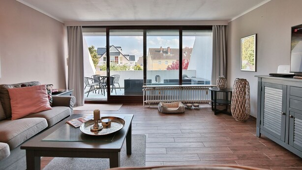 A modern living room with a sofa, coffee table, and a view of the city through large windows.