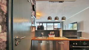 A modern kitchen with stainless steel appliances, a wooden countertop, and pendant lighting.