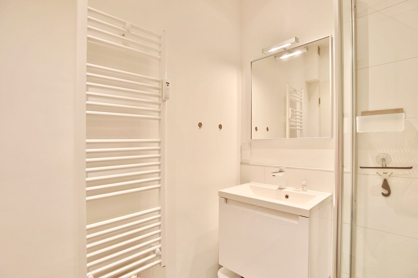 Un baño moderno con tocador blanco, espejo y cabina de ducha de vidrio.
