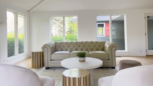 Un salón amplio con un sofá beige grande, una mesa de centro redonda blanca y una araña.