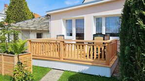 Una casa moderna con terraza de madera, paredes exteriores blancas y ventanas amplias.