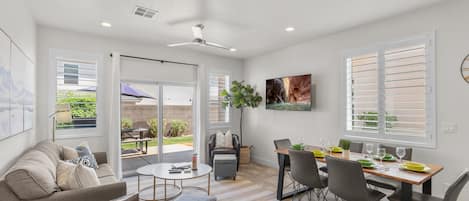 A modern living room with a sofa, coffee table, and dining table set for six.