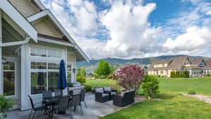 A house with a patio, outdoor furniture, and a view of a mountain range. - The Lakehouse/Snow Vacation Rental (Osoyoos)