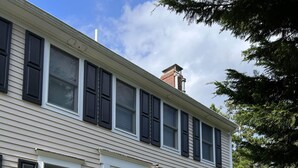 A two-story house with a front door, multiple windows, and a small garden with stepping stones. - Private Beach on Pond, Linens Included, Kayak & Canoe. All Rooms w/ Pond Views! (Chatham)