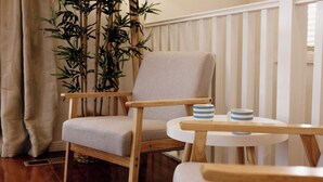 A wooden chair with a light-colored cushion, a small round table with a blue and white striped mug, and a bamboo plant in the background. - Family, Pet  & EV Friendly Home in Bowral Centre (Bowral)