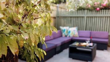 Un espace extérieur aménagé avec un canapé violet et une table basse.