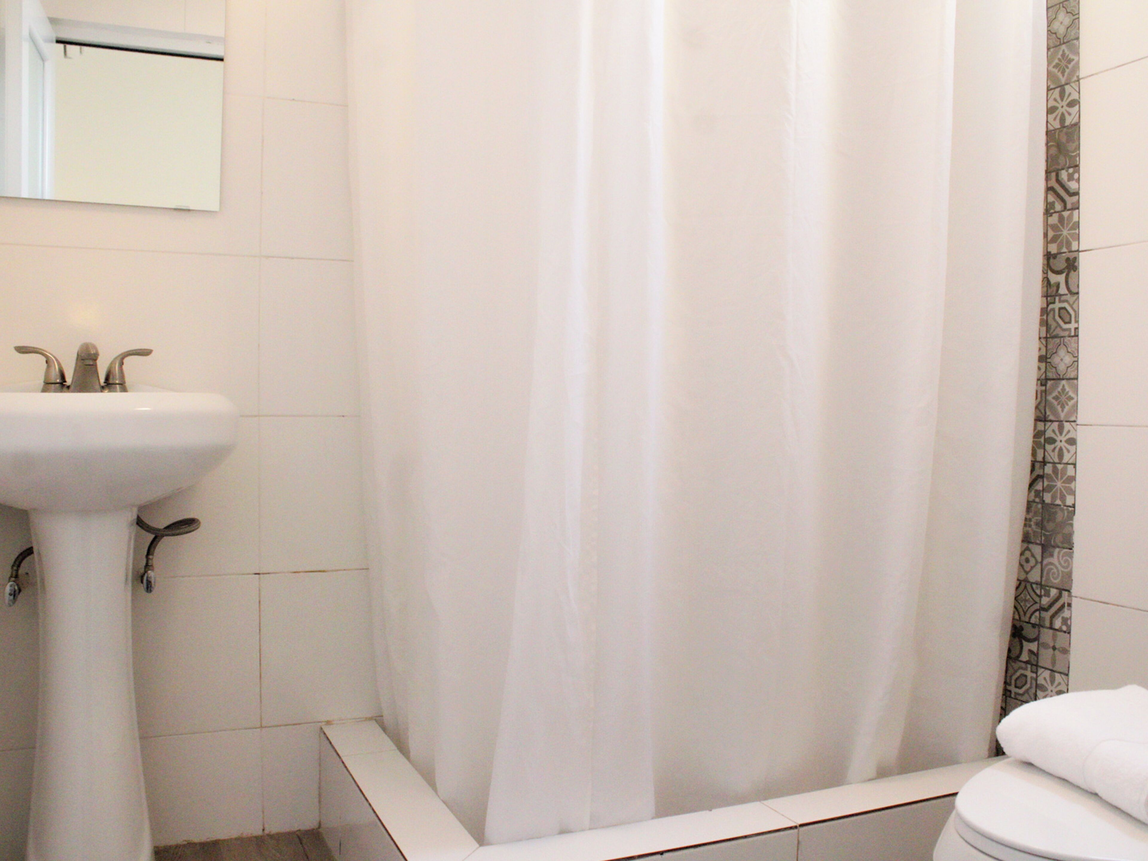 A bathroom with a white sink, a shower curtain, and a toilet.