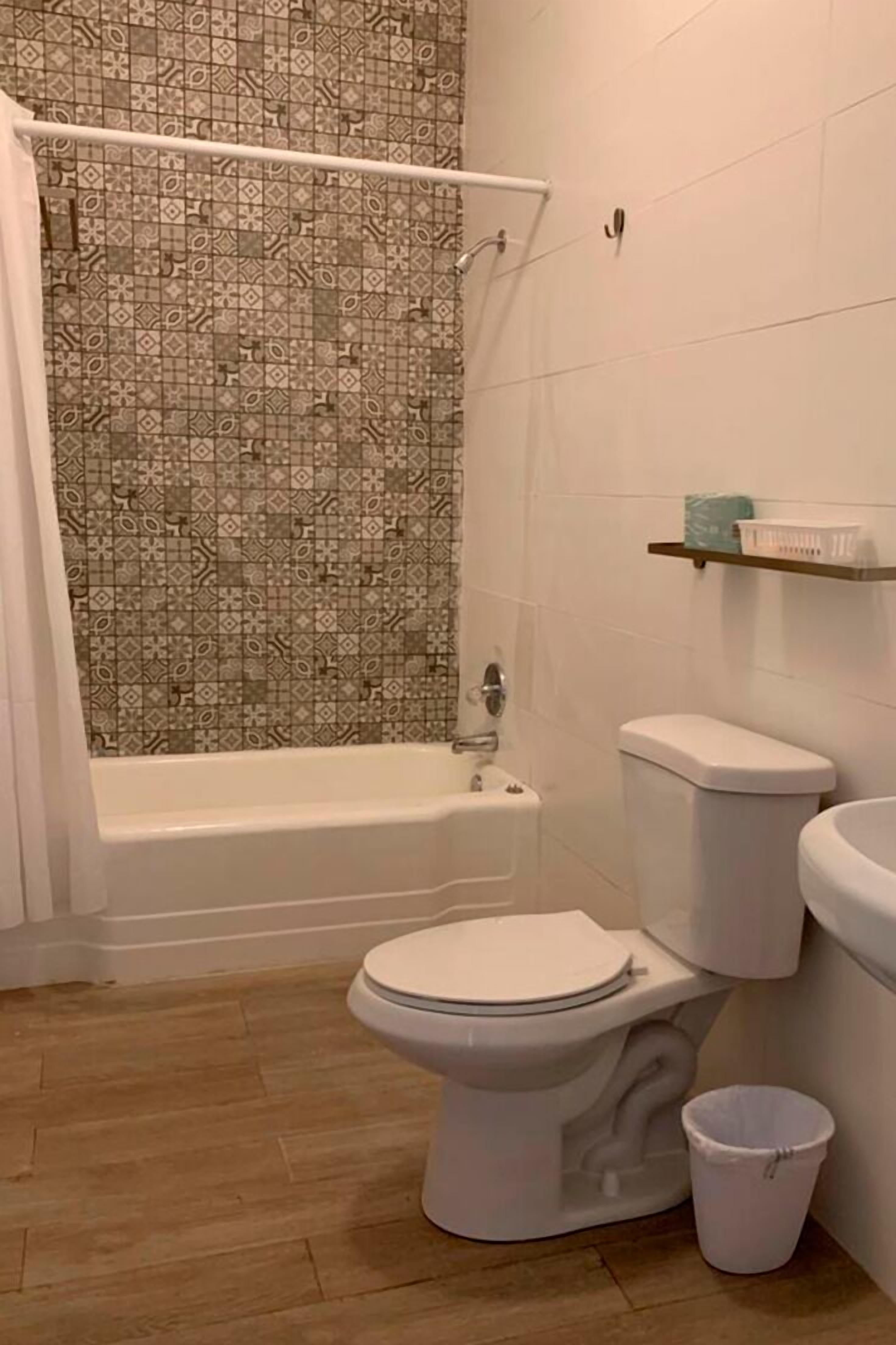 Un baño con ducha, inodoro y un estante pequeño con artículos de tocador.