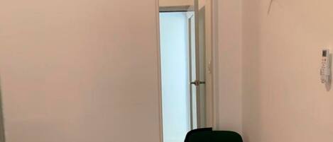 A small room with a bed, a chair, a mirror, and a window.