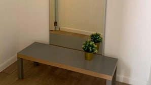 Ein Zimmer mit einem großen Spiegel, einer Bank und einem kleinen Topfpflanzen.