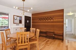 Un comedor con una mesa redonda de madera y sillas, un tablero de menú colgado en la pared y un revestimiento de pared de madera.