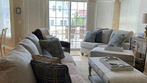 A living room with a high ceiling, a large window, and a sliding glass door leading to an outdoor area. - One off with Views! Long Beach Twsp. (Brant Beach)