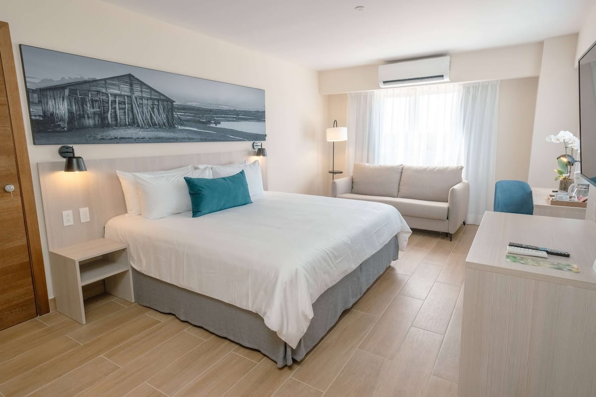 Ein Hotelzimmer mit Bett, Schreibtisch, Stuhl, Lampe und einem Bild an der Wand.