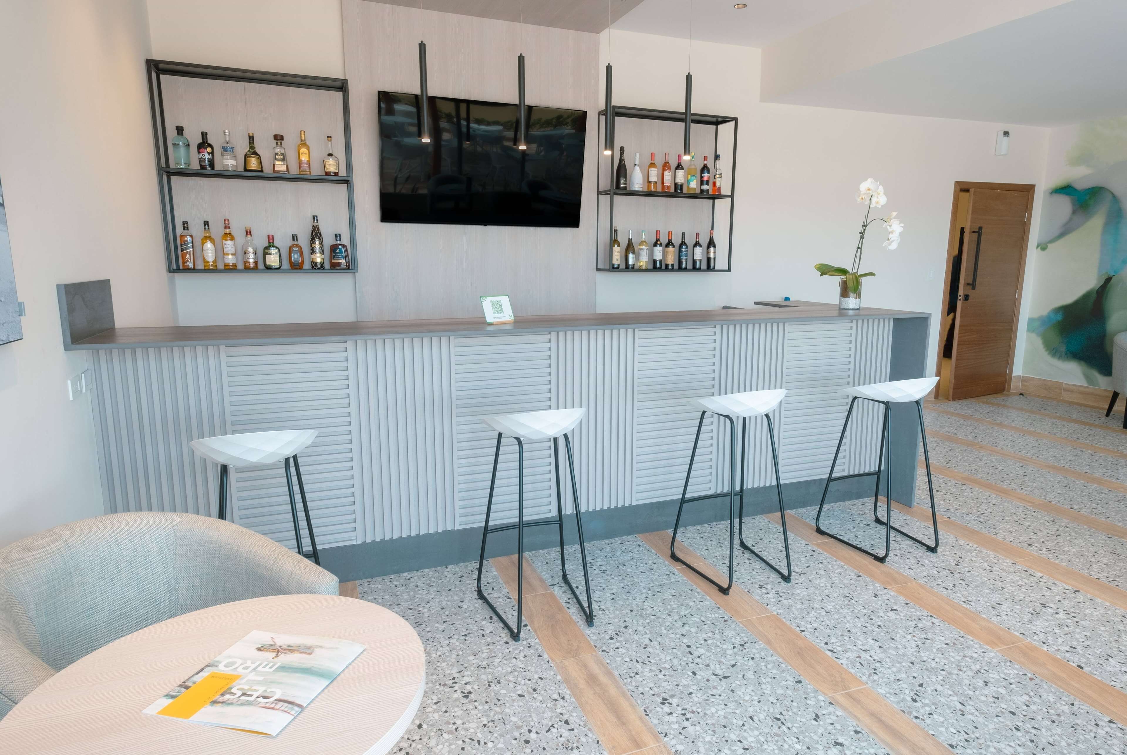 A bar area with a counter, stools, and shelves of bottles.