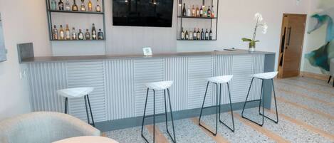 A bar area with a counter, stools, and shelves of bottles.