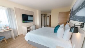 A hotel room with a large bed, a desk, a chair, a TV, and a painting on the wall.