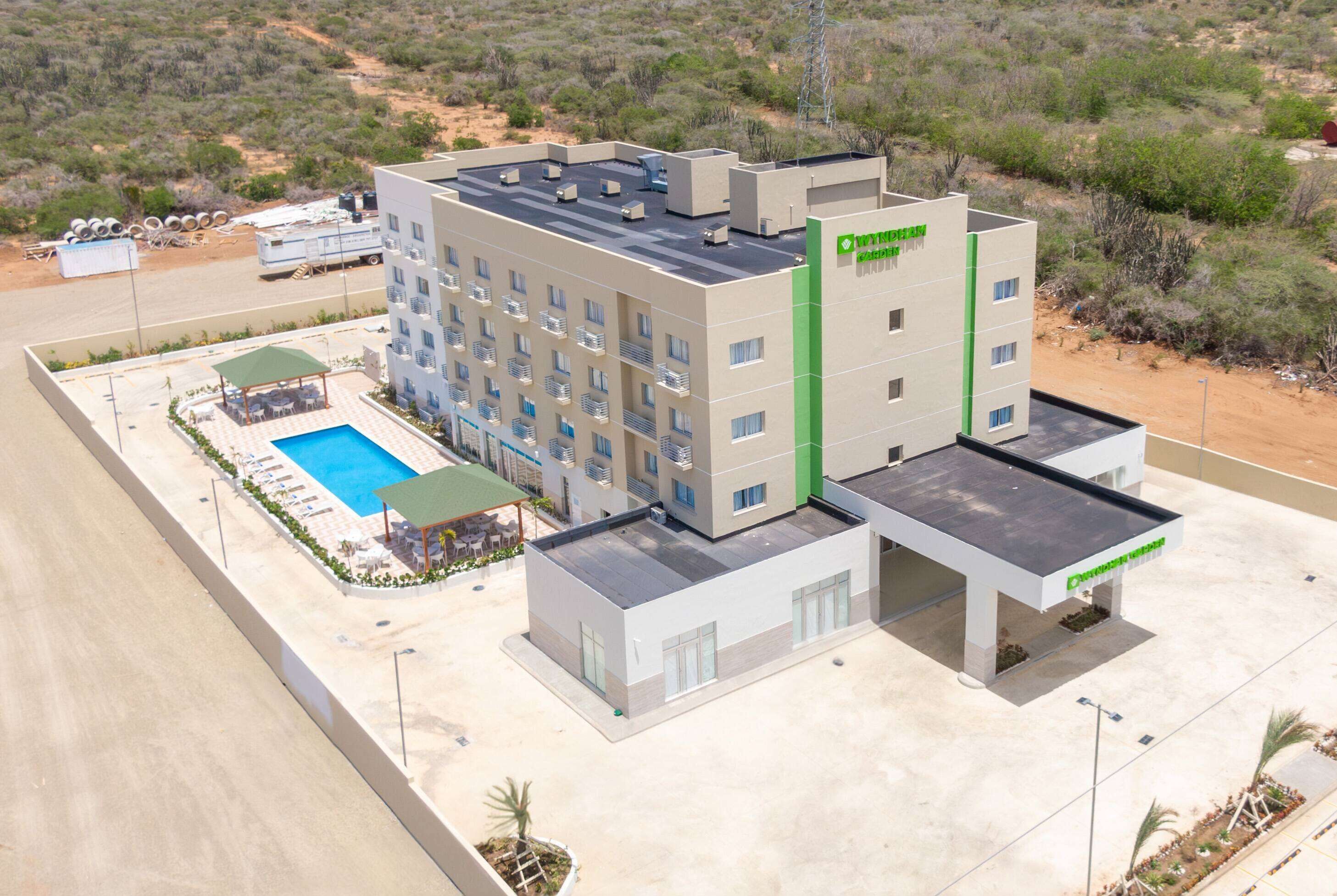 A hotel with a rooftop pool, multiple balconies, and a green vertical sign.