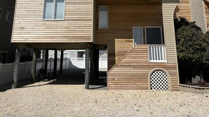 A multi-story wooden house with a balcony, a garage, and a small garden area. - Beautiful Townhome located near the beach in Beach Haven. (Beach Haven)