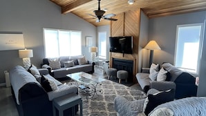 A spacious living room with a high wooden ceiling, a fireplace, multiple seating areas, and a television. - Beautiful Townhome located near the beach in Beach Haven. (Beach Haven)