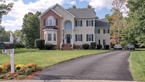 A two-story house with a brick section and a beige siding section, a driveway, and a mailbox with the number 10806. - Private bedroom and bath!  (Midlothian)