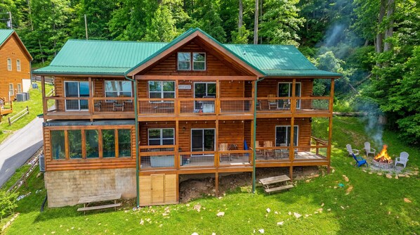 A multi-story log cabin with a green roof, multiple balconies, and a fire pit area.