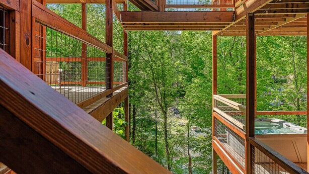 A wooden deck with multiple levels, surrounded by lush greenery.