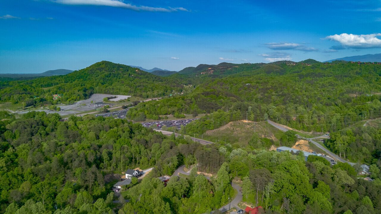 An aerial view of a hilly area with a parking lot, roads, and scattered buildings.