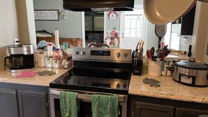 Een keuken met een fornuis, oven en diverse apparaten, zoals een koffiezetapparaat en een slowcooker.